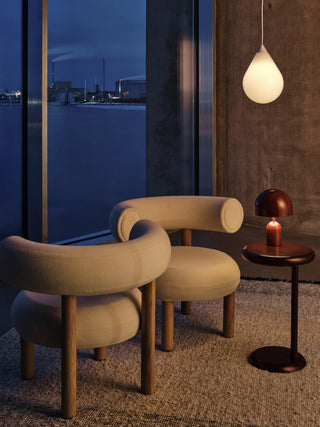 Tom Dixon Bell Portable Lamp in high-gloss burgundy on a side table beside lounge chairs