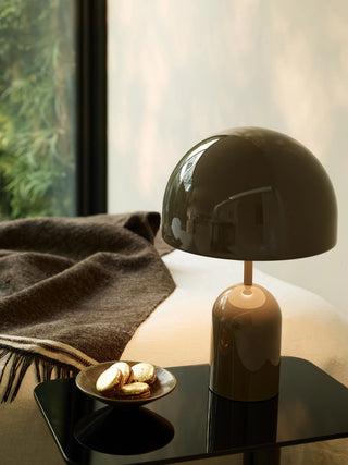 Tom Dixon Bell Portable Lamp in high-gloss taupe on a black side table beside a wool throw