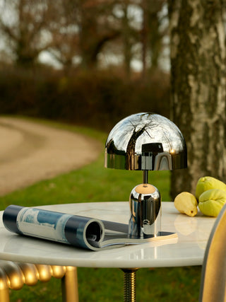 Tom Dixon Bell Portable Lamp in polished silver on an outdoor marble table