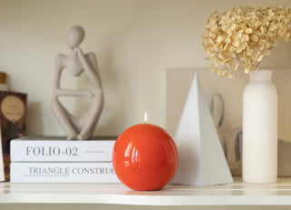 Ivory Meloria sphere candle beside its black gift box